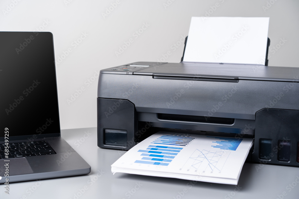 Printer and laptop on grey table in office Printer and laptop on grey table in office