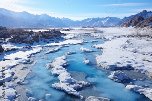 Arctic Flow: The Winter Sun Illuminates a Frozen River Winding Through a Snow-Kissed Mountain Landscape