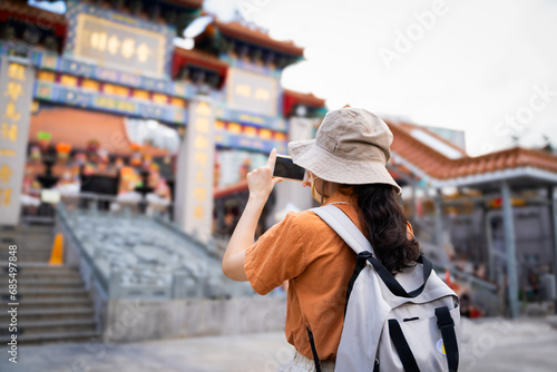 Back view of tourist women blogger or Influencer are Taking photo while traveling in Hong Kong with the blur background of a most popular Chinese temple in travel and solo travel concept.