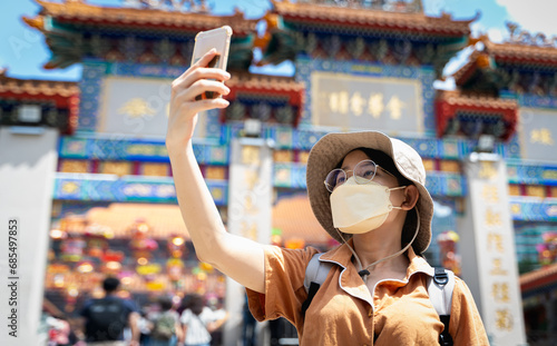 Tourist women blogger or Influencer are selfie photo while traveling in Hong Kong with the blur background of a most popular Chinese temple in travel and solo travel concept