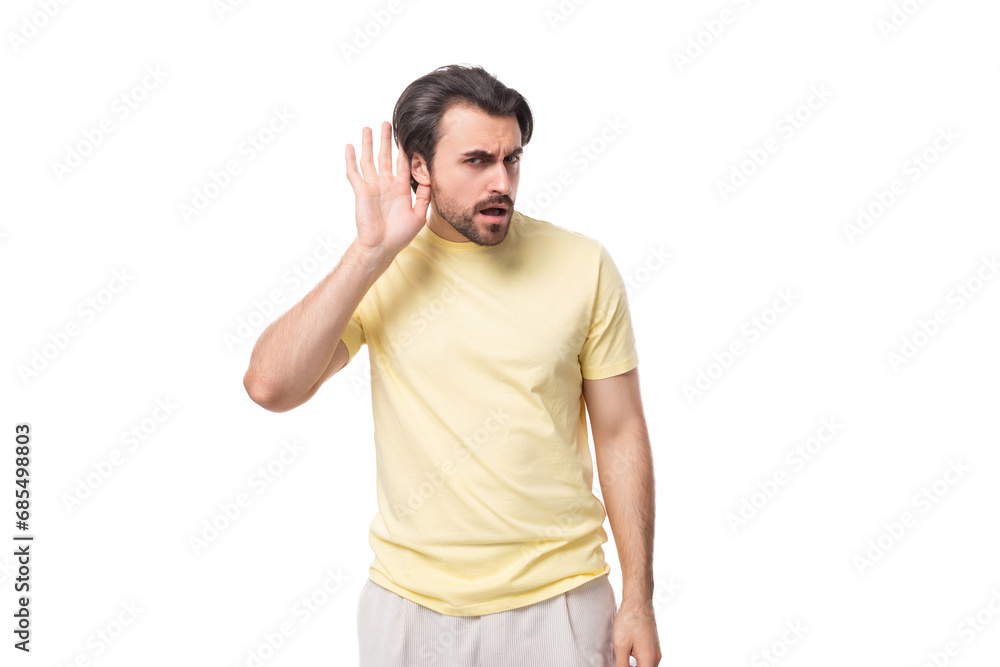 Fototapeta premium caucasian surprised brutal charming guy with a beard dressed in a summer t-shirt on a white background with copy space