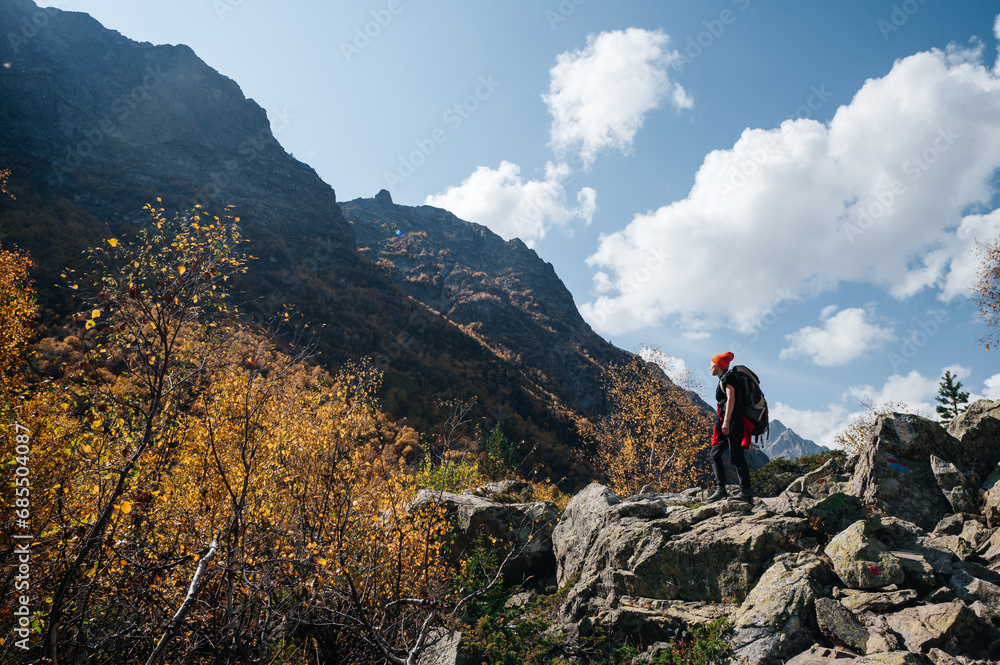 a girl with a backpack stands in the autumn mountains