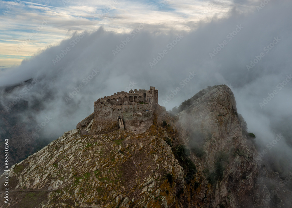 drone view of the Castello del Volterraio shrouded in morning fog and cloud