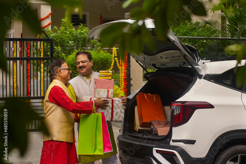Father and son unloading Diwali gifts from car trunk after shopping photo