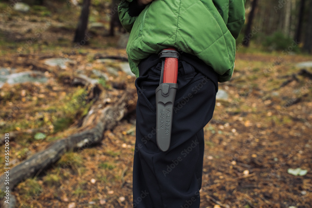 boy with a knife attached to his belt in the forest