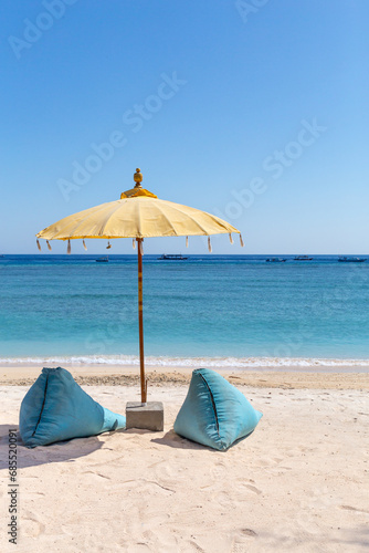 Bean bags and yellow umbrella at sandy beach of Gili Islands © Cavan