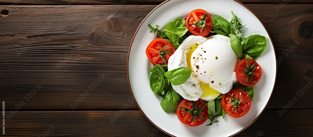 Top view of a white plate holding a burrata salad with tomatoes and basil.