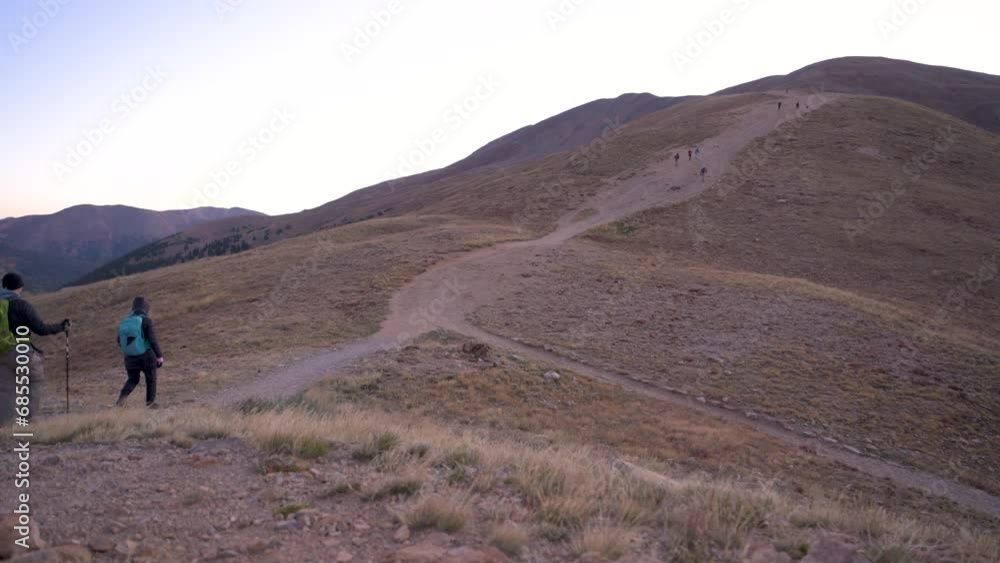 Couple hiking up steep mountain trail before sunrise, static Couple hiking up steep mountain trail before sunrise, static