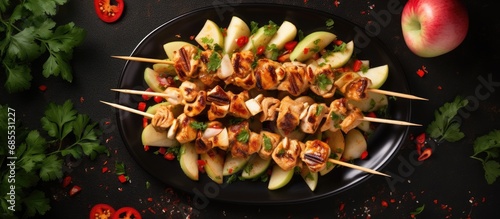 Top view of chicken skewers with apple slices and chili.