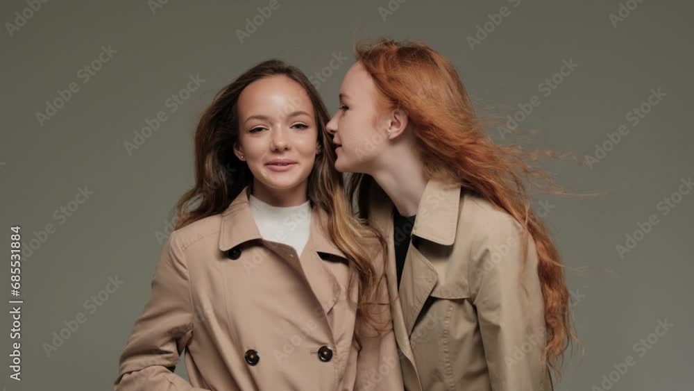 Two stylish models in a trench coat in the studio on a gray background. Two stylish models in a trench coat in the studio on a gray background.