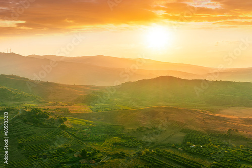 scenic rustic landscape with green hills and farms in a mountain valley during colorful cloudy sunset © Yaroslav