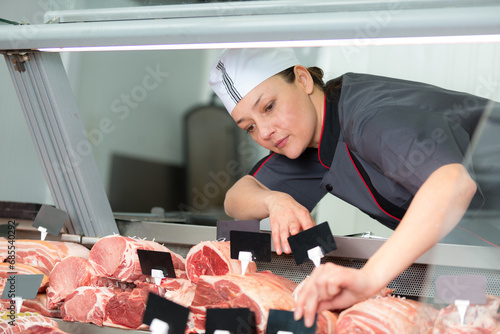 woman pork butcher cutting cooked ham with machine