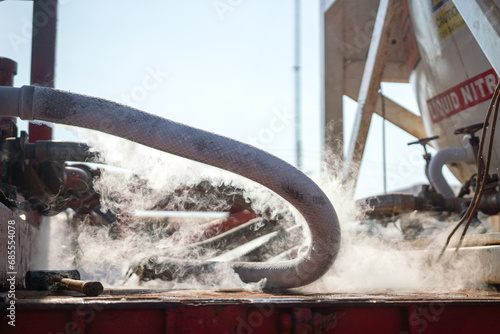 Liquid nitrogen pipeline with iced was exposed on the surface due to pressure differential during flowing. Industrial processing and equipment, close-up at the object. photo