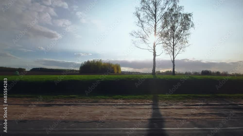 Roadway out of town. Plowed field, trees on background. Highway along rural area. View through right side window on passenger seat of car van wagon in motion. Spring in april. Sunny weather, evening Roadway out of town. Plowed field, trees on background. Highway along rural area. View through right side window on passenger seat of car van wagon in motion. Spring in april. Sunny weather, evening