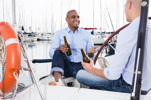  Couple of guys in blue shirts and jeans chatting on a private yacht in the port