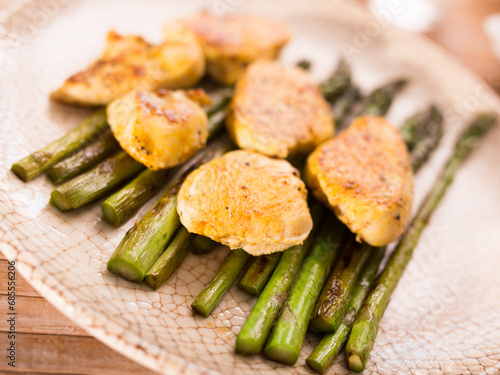 Fried chicken breast pieces with asparagus on white plate