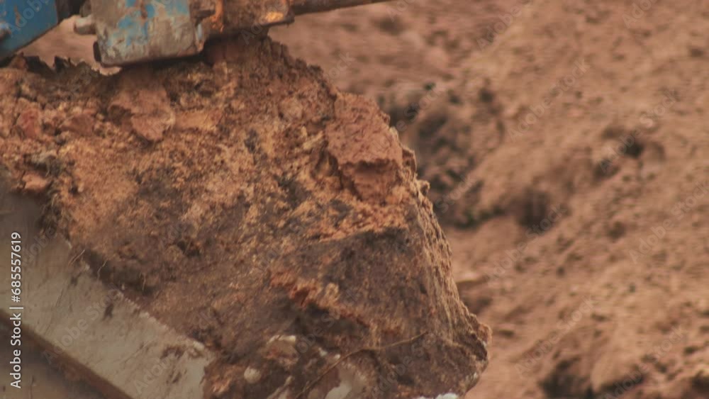 The excavator bucket digs a hole, pours out the earth. Construction works. Teeth on excavator bucket, industry. Copy space for text The excavator bucket digs a hole, pours out the earth. Construction works. Teeth on excavator bucket, industry. Copy space for text