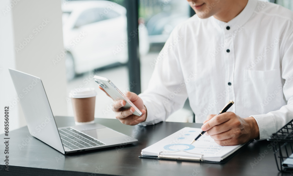 Young handsome man typing on tablet and laptop while sitting at the working wooden table office Young handsome man typing on tablet and laptop while sitting at the working wooden table office