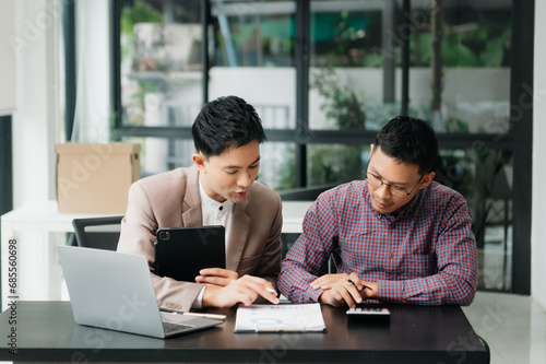 Businessman leading team meeting and using tablet and laptop computer with financial in co working office