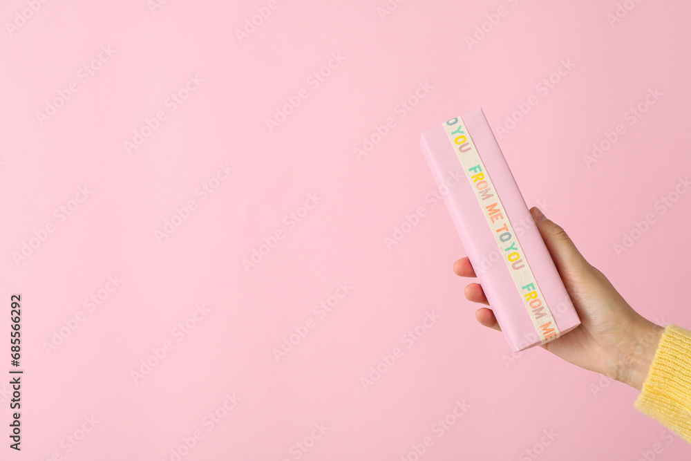 Gift box in female hand on pink background, space for text Gift box in female hand on pink background, space for text
