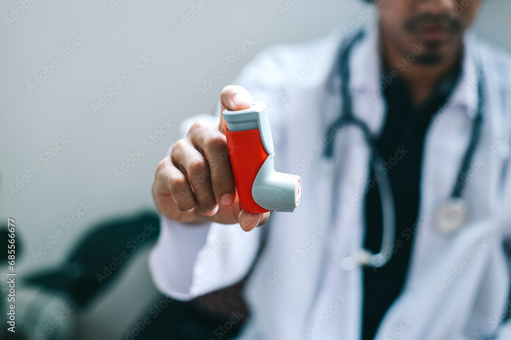 Male doctor holding and showing asthma inhaler. Medical portable equipment for asthma attack.  - obrazy, fototapety, plakaty 