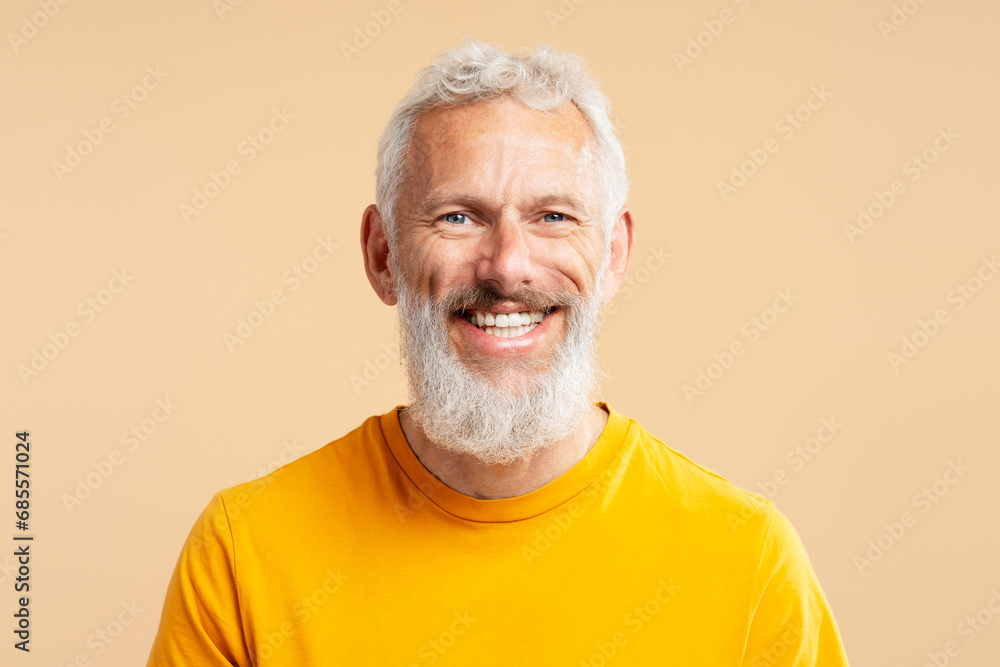 Closeup portrait handsome smiling 50 years old man with stylish gray hair wearing casual orange t shirt, looking at camera isolated on background. Health care, dental treatment concept Closeup portrait handsome smiling 50 years old man with stylish gray hair wearing casual orange t shirt, looking at camera isolated on background. Health care, dental treatment concept