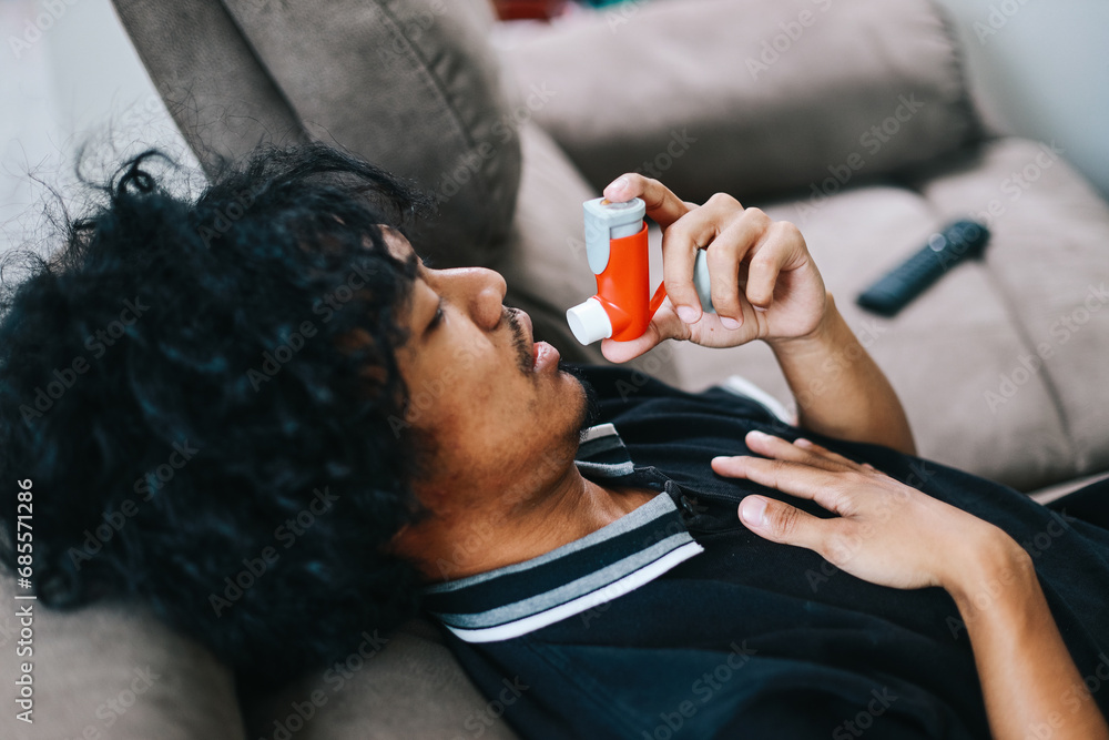 Man sitting on couch at home holding chest having difficulties ...