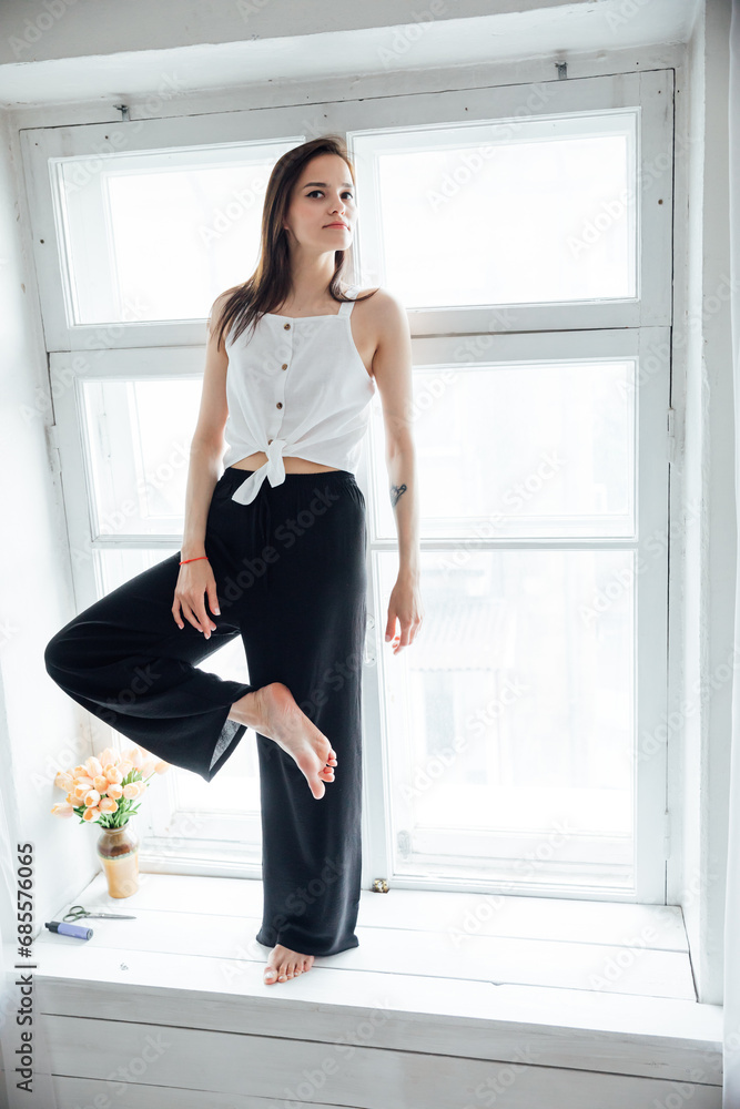 Portrait of a beautiful fashionable woman at the window in a white room Portrait of a beautiful fashionable woman at the window in a white room