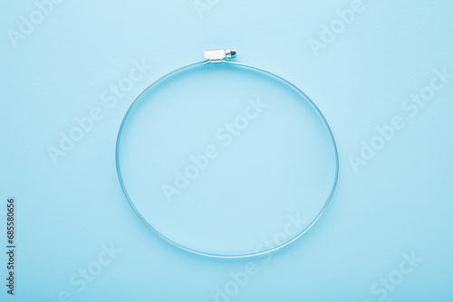 New metal hose clamp on light blue table background. Pastel color. Closeup. Top down view. photo