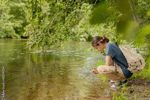 female tourist on the bank of a forest river, enjoying nature