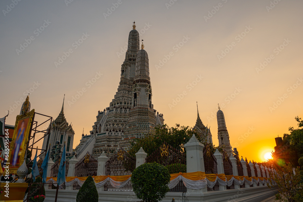 Fototapeta premium scenery sunset behind the large illuminated temple Wat Arun the biggest and tallest pagoda in the world beside Chaophraya river Bangkok, Thailand..pagoda in golden sunset popular landmark in Bangkok