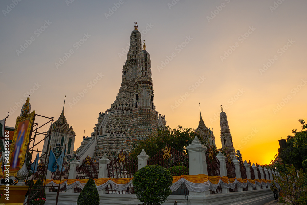 Fototapeta premium scenery sunset behind the large illuminated temple Wat Arun the biggest and tallest pagoda in the world beside Chaophraya river Bangkok, Thailand..pagoda in golden sunset popular landmark in Bangkok