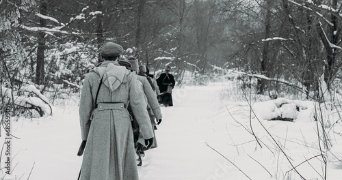 Naklejka Army on Marching. Men Dressed As White Guard Soldiers Of Imperial Russian Army In Russian Civil War s Marching Through Snowy Winter Forest. Historical Reenactment of Civil War. Black And White .