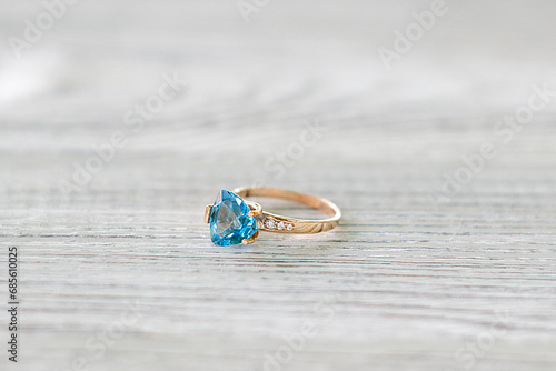 Gold ring with blue topaz on a light background
