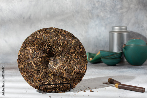 Quadro em tela Round flat disc of puer tea with puerh tea awl on gray background