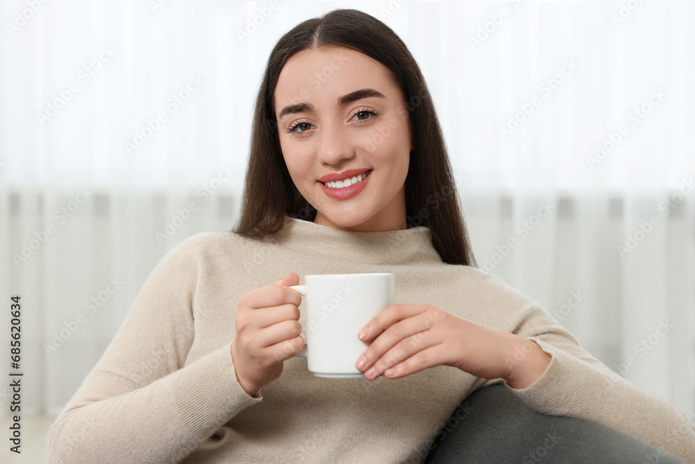 Happy young woman holding white ceramic mug at home Happy young woman holding white ceramic mug at home