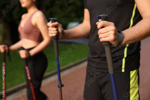 Couple practicing Nordic walking with poles outdoors, selective focus