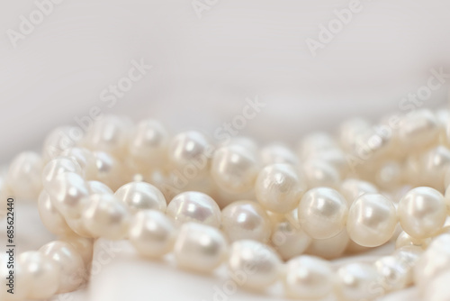 A string of pearls nestles softly on a light fabric, their subtle glow embodying elegance. It's a gentle nudge towards appreciating the enduring charm of natural beauty.