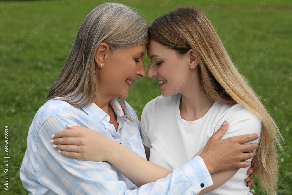 Obraz premium Happy mature mother and her daughter hugging outdoors