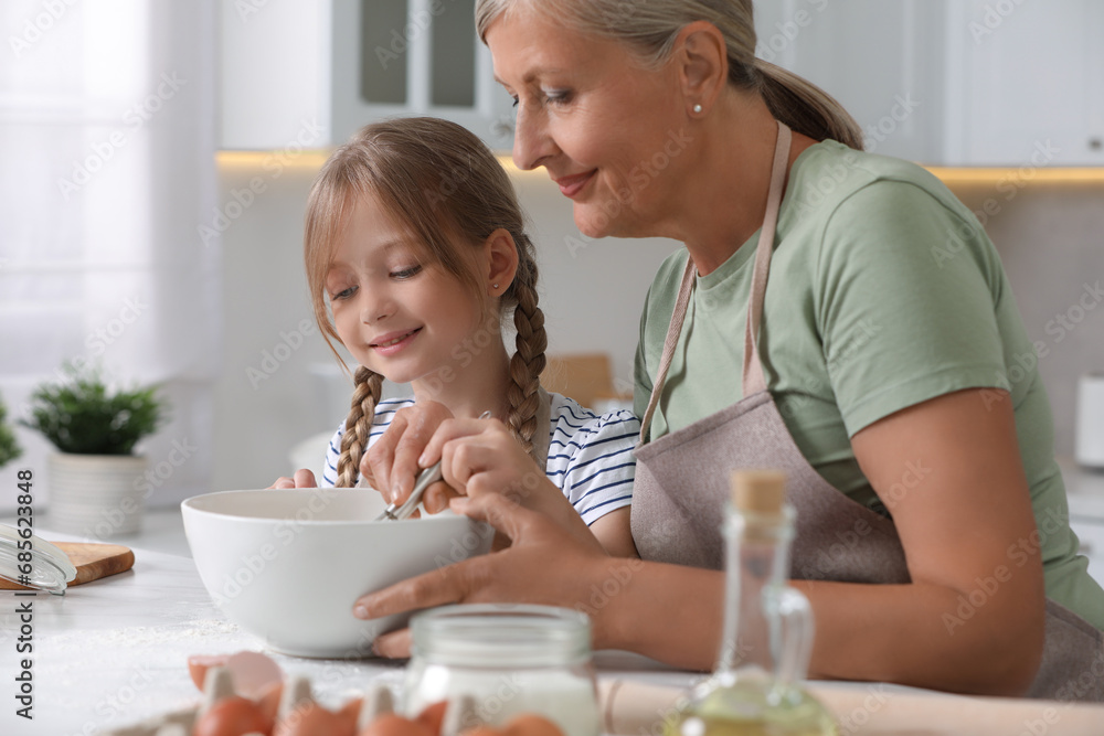 Happy grandmother with her granddaughter cooking together in kitchen Happy grandmother with her granddaughter cooking together in kitchen
