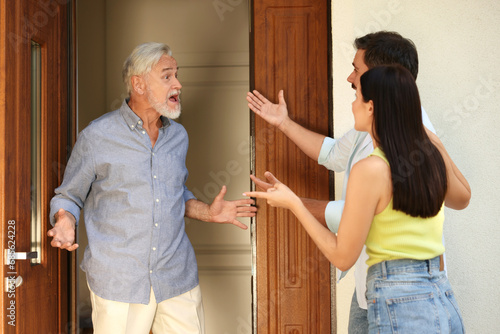 Neighbour`s quarrel. Young couple arguing with emotional senior man