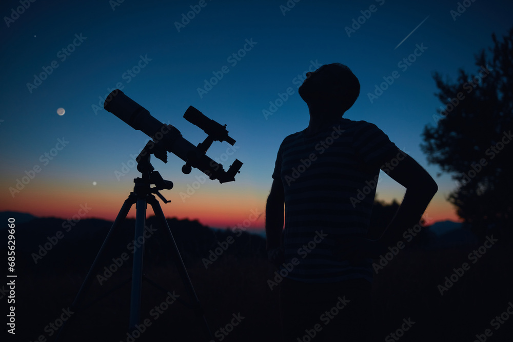 Astronomer looking at the starry skies and crescent Moon with a telescope.