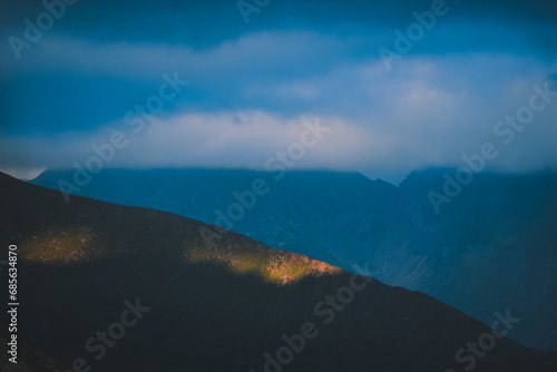 The ray of light hitting the side of a rocky mountain. Cloudy weather after a summer storm in the Carpathian Mountains of Romania