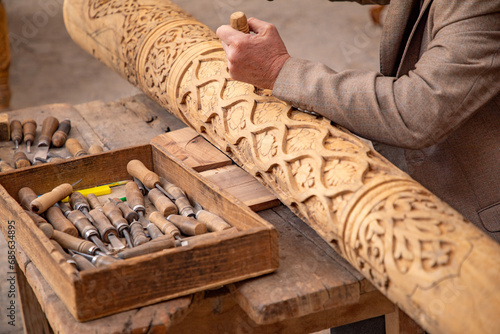 man crafting a wooden beam with his hand in Old traditional way, old traditional handcraft, Khiva, the Khoresm agricultural oasis, Citadel. photo