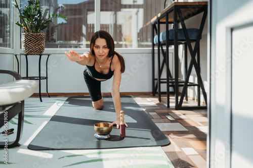 Determined woman practicing Balancing Table Pose on yoga mat at home photo