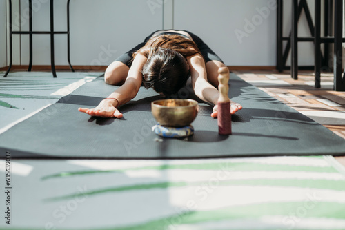 Woman practicing Balasana pose on yoga mat at home photo