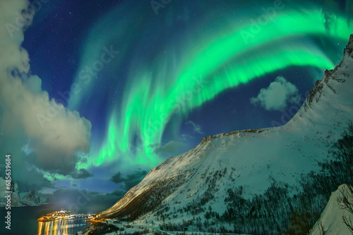 Norway, Troms og Finnmark, Green northern lights over mountains surrounding Oyfjord photo