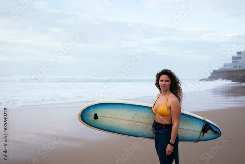 Confident young woman with surfboard at beach on vacation photo