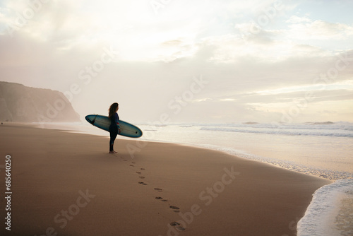 Footprints leading surfer with surfboard standing bear sea photo