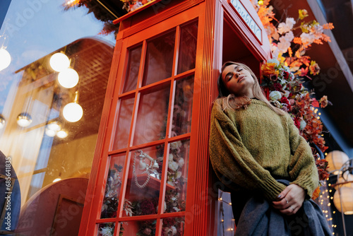 Obraz na plátně View to sad woman standing near retro telephone in payphone booth